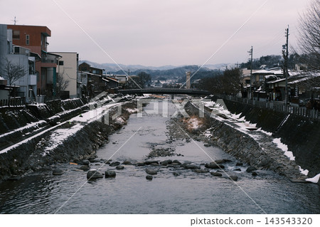 一條河面上還殘留著積雪,一座小鎮依偎在山巒之中。 一條河面上還殘留著積雪,一座小鎮依偎在山巒之中。 143543320