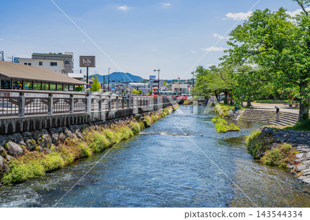 The clear waters of the Kanda River flowing through Fujinomiya City, Shizuoka Prefecture, under a refreshing early summer blue sky, and the surrounding townscape. The clear waters of the Kanda River flowing through Fujinomiya City, Shizuoka Prefecture, under a refreshing early summer blue sky, and the surrounding townscape. 143544334