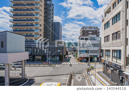 在靜岡縣，清澈湛藍的初夏天空下，富士宮車站前的城市景觀，可以看到十字路口和成排的公寓大樓。 143544518