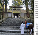 A Shinto priest and a sacred horse ascend the stone steps of a shrine: A scene of Japanese tradition and sacredness. 143544622