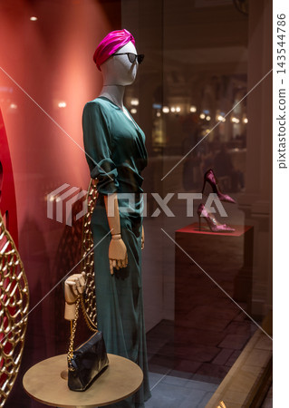 Mannequin in Green Draped Dress With Pink Turban and Sunglasses in Boutique Window Display Mannequin in Green Draped Dress With Pink Turban and Sunglasses in Boutique Window Display 143544786
