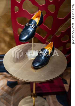 Black Leather Loafers With Horsebit Detail on Boutique Display Table in Fashion Store Window Black Leather Loafers With Horsebit Detail on Boutique Display Table in Fashion Store Window 143544792