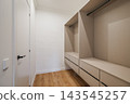 A modern, minimalist closet interior with light wood flooring. The space features built-in shelves and drawers, creating a clean and organized look. 143545257
