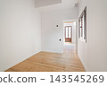 Empty room with white walls and wooden floor. A doorway leads to another room with natural light. Minimalist design and spacious layout. 143545269