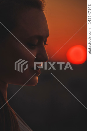 Woman Watching Sunset in Warm Evening Light Woman Watching Sunset in Warm Evening Light 143547148