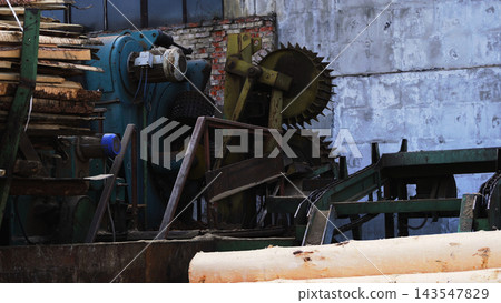 Industrial sawmill machinery processing timber logs into wooden boards for carpentry and construction materials Industrial sawmill machinery processing timber logs into wooden boards for carpentry and construction materials 143547829