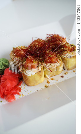 Sushi rolls presenting a gourmet meal, featuring salmon, cream cheese, pistachios, chili threads, and gold flakes 143547862