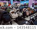 Rows of baby strollers in various colors on display in a retail store. 143548115