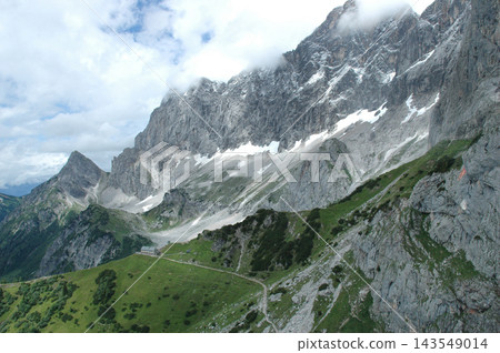 Panoramic view of Dachsteinsuedwandhuette below massive mountain walls Panoramic view of Dachsteinsuedwandhuette below massive mountain walls 143549014