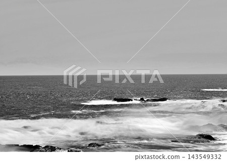 從江之島湘南大防波堤上拍攝的黑白長曝光照片,展現了岩石海岸和相模灣在強風中激起的白色浪花。 從江之島湘南大防波堤上拍攝的黑白長曝光照片,展現了岩石海岸和相模灣在強風中激起的白色浪花。 143549332