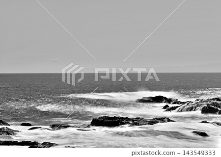Black and white, long exposure shot of the rocky shore and Sagami Bay with whitecaps rising in strong winds, as seen from the Enoshima Shonan Great Breakwater. Black and white, long exposure shot of the rocky shore and Sagami Bay with whitecaps rising in strong winds, as seen from the Enoshima Shonan Great Breakwater. 143549333