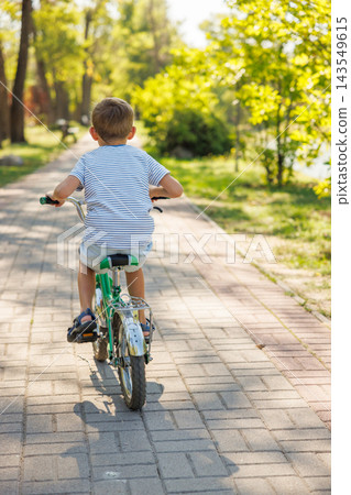 Young boy riding bicycle on park pathway Young boy riding bicycle on park pathway 143549615