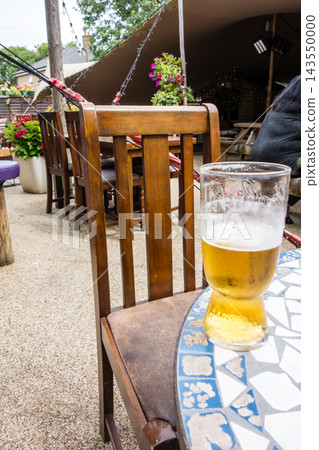 A pint of beer sits on a mosaic-patterned table in the bright sunlight at a pub in the suburbs of London. A pint of beer sits on a mosaic-patterned table in the bright sunlight at a pub in the suburbs of London. 143550000
