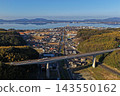 An aerial photograph of the city of Matsue, Shimane Prefecture, overlooking the elevated railway bridge and Lake Shinji. 143550162