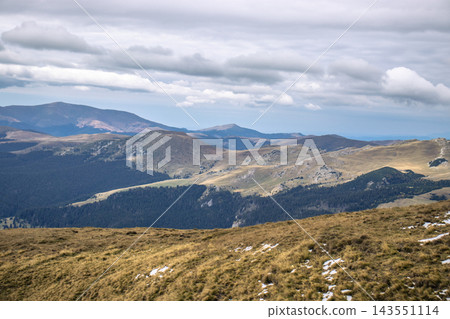 Autumn landscape with gold valley and winding trail through mountainside under dramatic sky Autumn landscape with gold valley and winding trail through mountainside under dramatic sky 143551114