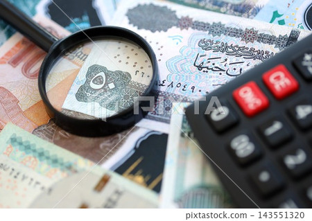 Egyptian pound currency money bills and calculator with magnifying glass. The concept of taxation 143551320