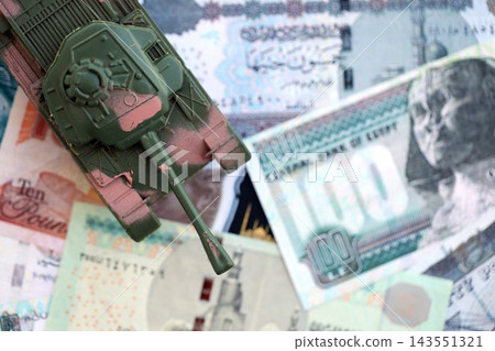 Egyptian pound currency money bills and toy tank. The concept of army funds and weapons sales Egyptian pound currency money bills and toy tank. The concept of army funds and weapons sales 143551321