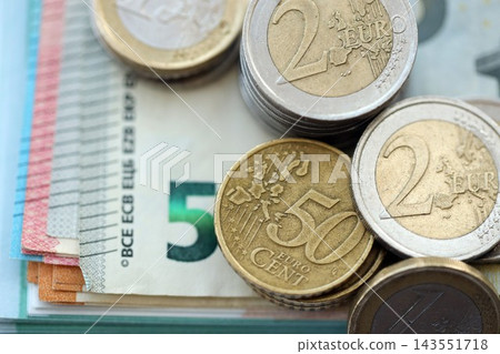 Eurozone euro money bills and cent coins pile on table. Eurozone coins on banknotes of EUR currency Eurozone euro money bills and cent coins pile on table. Eurozone coins on banknotes of EUR currency 143551718