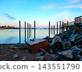 Old Wooden Pilings and Rocks Under Blue Sky 143551790