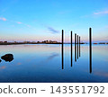 Weathered Wooden Posts Standing in Still Blue Water 143551792