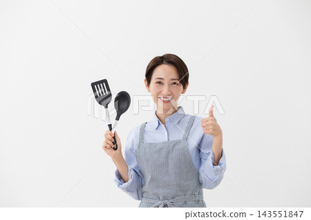 A cooking image of a woman holding a spatula and turner. A cooking image of a woman holding a spatula and turner. 143551847