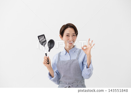 A cooking image of a woman holding a spatula and turner. A cooking image of a woman holding a spatula and turner. 143551848