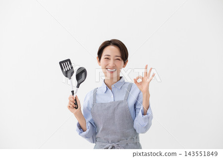 A cooking image of a woman holding a spatula and turner. A cooking image of a woman holding a spatula and turner. 143551849