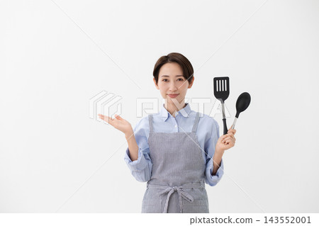 A cooking image of a woman holding a spatula and turner. A cooking image of a woman holding a spatula and turner. 143552001