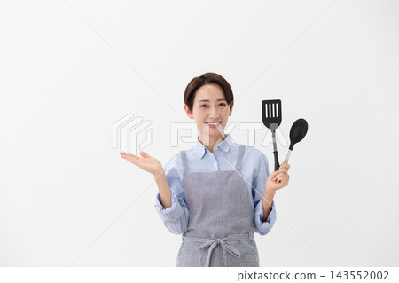 A cooking image of a woman holding a spatula and turner. 143552002