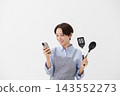 An image of a woman checking a recipe on her smartphone. 143552273