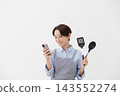 An image of a woman checking a recipe on her smartphone. 143552274
