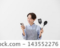An image of a woman checking a recipe on her smartphone. 143552276