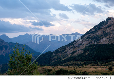Green Mountain Peak Under Soft Evening Clouds. A green mountain peak rises under soft evening clouds in the Spanish Pyrenees near Formigal, Spain, a serene and majestic landscape of the Tena Valley Green Mountain Peak Under Soft Evening Clouds. A green mountain peak rises under soft evening clouds in the Spanish Pyrenees near Formigal, Spain, a serene and majestic landscape of the Tena Valley 143552301