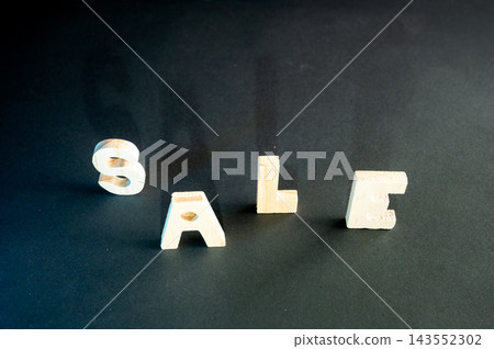 Minimal SALE Concept on a Dark Background. Wooden letters spelling SALE on a dark moody background with soft colorful lighting, a creative conceptual image of discounts, bargains and seasonal shopping Minimal SALE Concept on a Dark Background. Wooden letters spelling SALE on a dark moody background with soft colorful lighting, a creative conceptual image of discounts, bargains and seasonal shopping 143552302