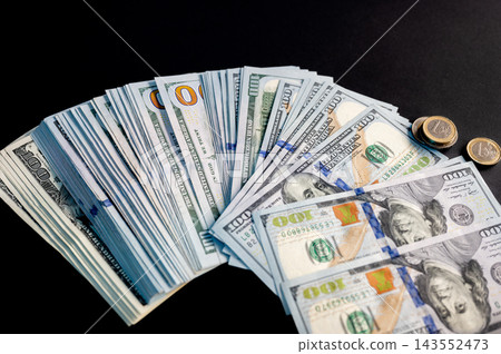 Stacks and Fans of Hundred Dollar Bills. Stacks and fans of US hundred dollar bills on a dark background, a creative concept of cash, money, wealth and financial success. 143552473