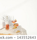 Two rose wine glasses with summer cocktails and dried fruit appetizers. Tropical light background with palm shadow. 143552643