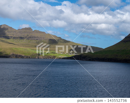 Calm sound between steep green mountains in the Faroe Islands. Calm dark water fills the sound between steep green mountains under a bright summer sky in the northern Faroe Islands. Peaceful island Calm sound between steep green mountains in the Faroe Islands. Calm dark water fills the sound between steep green mountains under a bright summer sky in the northern Faroe Islands. Peaceful island 143552736