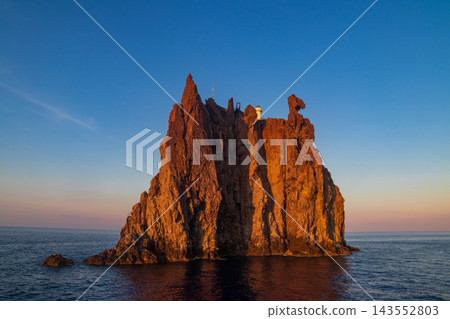 Scenic view of the volcanic island Strombolicchio with a historic white lighthouse rising from the blue Tyrrhenian sea, Aeolian archipelago, Sicily, Italy 143552803