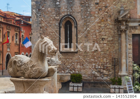 Selective focus on a stone sea horse sculpture of the baroque Quattro Fontane fountain with the medieval Duomo cathedral facade in background, Taormina, Sicily Selective focus on a stone sea horse sculpture of the baroque Quattro Fontane fountain with the medieval Duomo cathedral facade in background, Taormina, Sicily 143552804