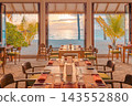 Inviting beach restaurant tables ocean view terrace lush palms bright tropical resort dining daylight. Scenic travel hospitality vista. Exotic dining getaway ambience 143552880