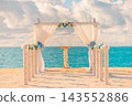 Romantic beach wedding arch draped fabric flowers vivid turquoise lagoon blue sky tropical ceremony. Luxury destination wedding celebration. Exotic bridal elopement 143552886