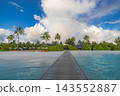 Wooden jetty leading overwater villas vivid turquoise Maldives lagoon rainbow blue sky bright shore. Scenic travel wanderlust vista. Exotic dream destination journey 143552887