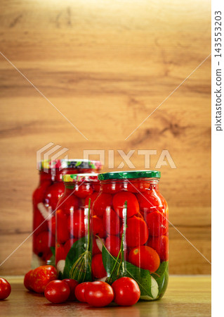 Traditional pickled tomatoes with dill and garlic in glass jars 143553203