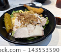 Rows of prepared sandwiches with sliced meat, lettuce, pickles, cheese, and crispy onion topping are arranged in black catering trays. 143553590