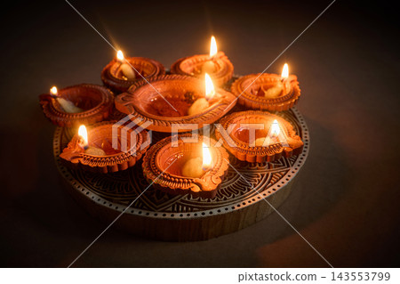 Burning diwali clay oil lamps on dark background Burning diwali clay oil lamps on dark background 143553799