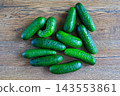 Fresh green whole cucumbers lie scattered on dark wooden surface. Healthy eating, organic farming, and raw agricultural food 143553861