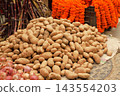 Potatoes and marigold flower arrangements displayed in a market in Kathmandu, Nepal. 143554203