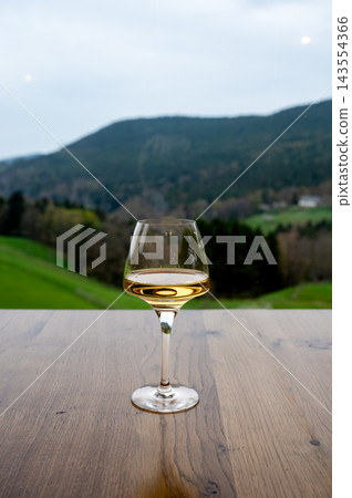 Hilltop wine relaxation overlooking vineyard countryside. Peaceful hilltop wine moment overlooking Alsace vineyard countryside with rolling green hills stretching to horizon, calm outdoor relaxation 143554366
