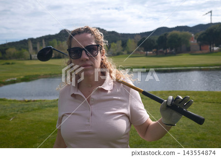Middle aged woman playing golf on a green golf course outdoors Middle aged woman playing golf on a green golf course outdoors 143554874