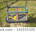 Empty Child Swing With Bright Yellow Leaf on Worn Playground Seat in Autumn Park 143555105